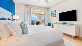Wave painting and white sideboard facing the bed, with the curtained terrace and sea beyond, St. Peter's Bay 404 in Barbados