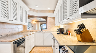 Lattice-fronted cupboards, speckled worktops and a tiled splashback in the U-shaped kitchen, St. Peter's Bay 404, Barbados