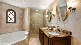 St. Peter's Bay 404 bathroom with twin basins, oval tilting mirrors, a glass-enclosed shower and a white bath, Barbados