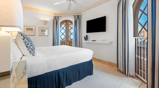 Navy-and-white bedroom with striped curtains and arched lattice doors at St. Peter's Bay 404 near Speightstown, Barbados