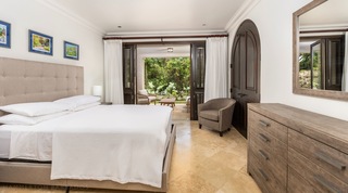 Guest bedroom with louvred doors onto a shaded garden patio at Tree House Villa 5, a villa rental in Barbados