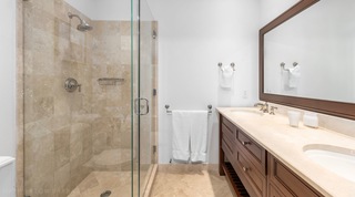 Stone tiled shower and dark wood double vanity at Tree House Villa 5, luxury villa in Barbados