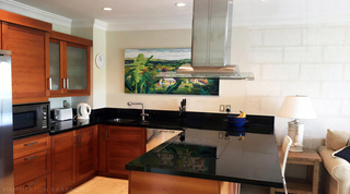 Kitchen with warm wood cabinets and black granite worktops at Waterside 402, Barbados