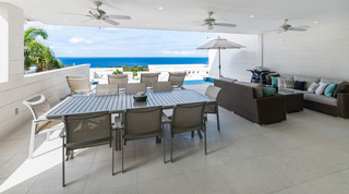 Open covered terrace at Westmoreland Hills 25 with dining table and wicker sofa facing the ocean, Barbados