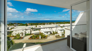 Balcony at Westmoreland Hills 25 looking through full-height glass across the community to the sea, Barbados