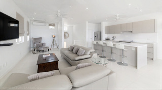 Open-plan lounge with breakfast bar and dark wood coffee table at Westmoreland Hills 25, St. James, Barbados