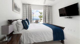 Queen bedroom at Westmoreland Hills 25 with dark wood bed and sea view through the terrace door, Barbados